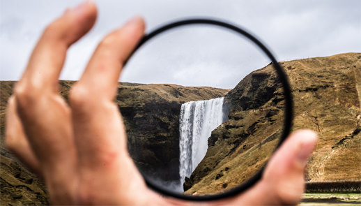 Person holding up a lense to see a waterfall in full clarity